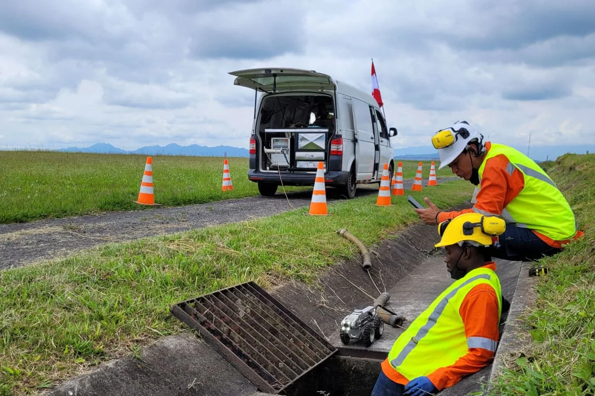 Cuadrilla de Pacific Group con van de inspección y robot CCTV diagnosticando red de alcantarillado en campo abierto, Colombia