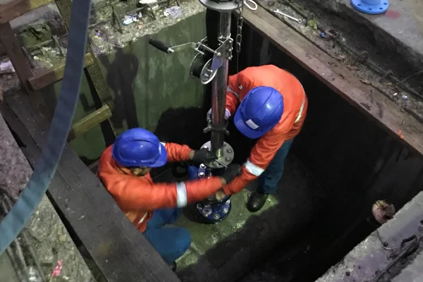 Técnicos realizando instalación y mantenimiento de equipos en red subterránea de acueducto para detección de fugas y control hidráulico.
