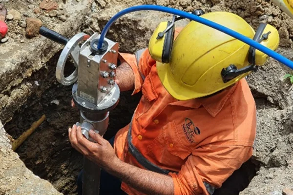 Técnico especializado realizando instalación y mantenimiento de válvula en red subterránea de acueducto durante trabajos de infraestructura hidráulica.